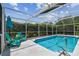 Relax by the pool in the screened enclosure complete with an umbrella and chairs, providing a serene outdoor oasis at 6006 Chellas Ct, Lutz, FL 33558