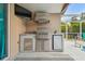 Covered outdoor kitchen area with a stainless steel grill and mini-fridge with a view of the pool at 6006 Chellas Ct, Lutz, FL 33558