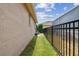 A narrow strip of well-maintained grass runs alongside the property, bordered by a black fence and lush greenery at 6006 Chellas Ct, Lutz, FL 33558