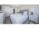 Bedroom with white and gray decor featuring a comfortable bed, dressers, and beach views at 6265 Sun Blvd # 115, St Petersburg, FL 33715