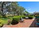 Relaxing brick patio shaded by a large tree and lush landscaping, perfect for outdoor living at 12904 Teakwood Ln, Hudson, FL 34667