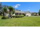 Charming home featuring a well-manicured lawn and lush landscaping, including palm trees and hedges at 12904 Teakwood Ln, Hudson, FL 34667