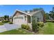 View of the home's two-car garage, manicured lawn, and landscaping with beautiful shrubs at 12904 Teakwood Ln, Hudson, FL 34667