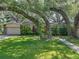 Inviting home with well-manicured lawn, mature trees, and charming stone accents and attached garage at 14350 11Th St, Dade City, FL 33523