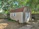 Wooden storage shed with a barn-style roof, double doors, and a small window in a backyard setting at 14350 11Th St, Dade City, FL 33523