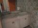Bathroom featuring a double sink vanity with marble countertops and patterned wallpaper at 14614 Lake Magdalene Cir, Tampa, FL 33613