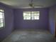 Spacious purple bedroom with natural light from two windows and a ceiling fan at 14614 Lake Magdalene Cir, Tampa, FL 33613