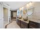Bathroom featuring double sinks, stone accent wall, granite counters, and a tiled shower at 1915 Belleair Rd, Clearwater, FL 33764