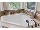 Bright bathroom featuring a soaking tub with marble surround and natural light at 1915 Belleair Rd, Clearwater, FL 33764
