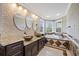 Beautiful bathroom featuring dual sinks, decorative mirrors, a soaking tub, and lots of natural light at 1915 Belleair Rd, Clearwater, FL 33764