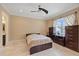 Bright bedroom featuring neutral walls, a ceiling fan, travertine floors, and dark wood furniture at 1915 Belleair Rd, Clearwater, FL 33764