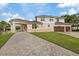 A charming home with brick-paved driveway, arched entryway, a three-car garage, and a well-maintained lawn at 1915 Belleair Rd, Clearwater, FL 33764