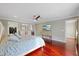Bright main bedroom featuring a ceiling fan, wood floors, and access to the en-suite bathroom and walk-in closet at 1915 Belleair Rd, Clearwater, FL 33764
