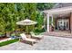 Outdoor living with sun loungers and outdoor kitchen overlooking the pool and lush landscaping at 29540 Chapel Park Dr, Wesley Chapel, FL 33543
