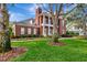 Brick home with a well-manicured lawn, mature tree, and traditional architectural details at 29540 Chapel Park Dr, Wesley Chapel, FL 33543