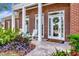 Charming home entrance with white rocking chairs, colorful foliage, and a welcoming front porch at 29540 Chapel Park Dr, Wesley Chapel, FL 33543
