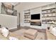Living room featuring custom built-ins with a fireplace and large screen TV over tan colored sectional sofa at 29540 Chapel Park Dr, Wesley Chapel, FL 33543