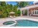Inviting backyard pool and spa with sun loungers and covered seating near an outdoor kitchen at 29540 Chapel Park Dr, Wesley Chapel, FL 33543