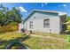 Side view of a quaint home featuring a grassy backyard with a small garden bed, chair, and fence at 3105 Gordon Ct, Tampa, FL 33619