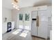Kitchen area showcasing white cabinets, refrigerator, french doors to the backyard, and modern light fixture at 3404 33Rd Street W Ct, Bradenton, FL 34205