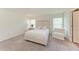A light and airy bedroom boasts a white bed with a chair and natural light streaming through the windows at 3879 E Price Blvd, North Port, FL 34288