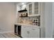 Modern bar area with custom stone backsplash, floating shelves, and wine fridge at 426 Islebay Dr, Apollo Beach, FL 33572