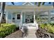 Charming light blue home featuring a welcoming front porch, lush landscaping, and a well-maintained lawn at 426 Islebay Dr, Apollo Beach, FL 33572