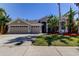 Charming home with a three car garage and tropical landscaping with nice curb appeal under a clear, blue sky at 476 Denise St, Tarpon Springs, FL 34689