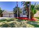 Charming home with well-manicured yard and tropical landscaping on a sunny day with a clear, blue sky at 476 Denise St, Tarpon Springs, FL 34689
