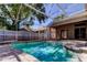 Inviting screened-in pool with brick pavers and privacy fence surrounded by lush, tropical landscaping at 476 Denise St, Tarpon Springs, FL 34689