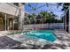 Relaxing screened-in pool with brick pavers and privacy fence surrounded by lush, tropical landscaping at 476 Denise St, Tarpon Springs, FL 34689