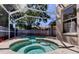 Inviting spa with brick pavers in screened-in pool area surrounded by lush landscaping and privacy fence at 476 Denise St, Tarpon Springs, FL 34689