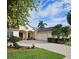 Charming home with a manicured lawn, palm trees, and a paver driveway leading to an attached two-car garage at 522 Planters Manor Way, Bradenton, FL 34212
