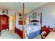 The main bedroom features a beautiful four-poster bed with floral bedding, carpeted floor, and a classic armoire at 522 Planters Manor Way, Bradenton, FL 34212