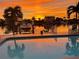Sunset over a tranquil backyard pool with palm tree reflections and boat dock at 533 Lillian Dr, Madeira Beach, FL 33708