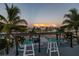 Enjoy the intercoastal view from this home's balcony with string lights, palms, and seating at 533 Lillian Dr, Madeira Beach, FL 33708