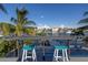 Waterfront home featuring a balcony with waterfront views and turquoise barstools under a partially cloudy, bright blue sky at 533 Lillian Dr, Madeira Beach, FL 33708