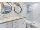 Bright bathroom with double sinks, stylish mirrors, sleek white cabinets, and a glass-enclosed shower at 533 Lillian Dr, Madeira Beach, FL 33708