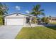 Charming single-story home featuring a well-manicured lawn, mature trees, and an attached two-car garage at 533 Lillian Dr, Madeira Beach, FL 33708