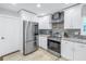 Updated kitchen features stainless steel appliances, white cabinets, granite counters, a stylish backsplash and neutral colored flooring at 533 Lillian Dr, Madeira Beach, FL 33708