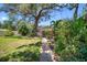 Spacious backyard showcasing mature trees, lush greenery, a stone pathway, and an outdoor bench for relaxation at 568 La Plaza S Ave, St Petersburg, FL 33707