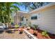 Charming home exterior with a cozy front porch, complemented by lush landscaping, colorful flowers, and a tropical palm tree at 568 La Plaza S Ave, St Petersburg, FL 33707