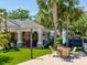 Exterior view of an outdoor seating area with manicured grass, tropical plants, and view of community buildings at 6910 Rock Springs Way, Tampa, FL 33625