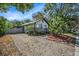 Charming home featuring tropical landscaping, a small front porch, and a well-maintained, light gray picket fence at 7309 N Huntley Ave, Tampa, FL 33604