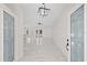 Open-concept living area showcasing decorative front doors, a modern chandelier, and sleek, marble flooring at 7372 Madrid Rd, Weeki Wachee, FL 34613