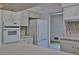 Open kitchen with white appliances, mosaic backsplash, and ample cabinet space for storage at 7802 N 53Rd St, Tampa, FL 33617