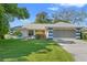 Charming single-story home featuring a manicured lawn, colorful accents, and an attached two-car garage at 8195 Wooden Dr, Spring Hill, FL 34606