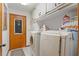 Laundry room with white washer and dryer, upper cabinets, tile flooring and wooden door at 8195 Wooden Dr, Spring Hill, FL 34606