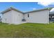 View of the rear exterior of the home and side yard, including landscaping, utilities and covered patio at 10493 Grail Ave, Englewood, FL 34224