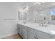 Bathroom with double sinks, gray cabinets, a large mirror, and a glass-enclosed shower at 10493 Grail Ave, Englewood, FL 34224